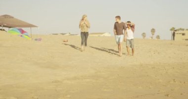 Bir grup arkadaş sahilde yürüyor.