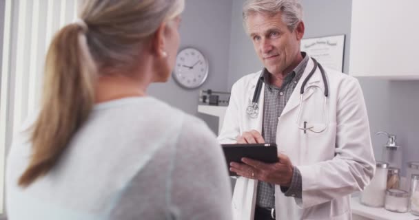 Ένας Ώριμος Γιατρός Που Εξετάζει Φάκελο Του Ασθενούς Ένα Δισκίο — Αρχείο Βίντεο
