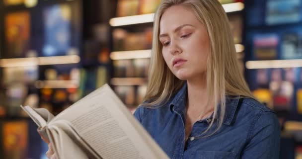 白人年轻女子在书店里翻阅一本她很好奇的书 漂亮的女性在浏览当地书店的时候看书 — 图库视频影像