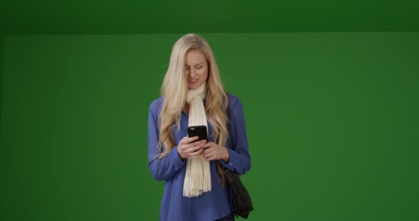 一个戴着围巾的年轻白人女孩在绿色屏幕上等待时使用了她的智能手机 在绿色屏幕上键入或合成 — 图库视频影像