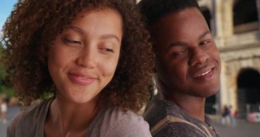 Şirin Afro-Amerikan çift sırtüstü oturup gülümsüyor ve gülüyor. Milenyum erkeği ve dişisi Roma 'da balayının tadını çıkarırken birbirlerine yaslanıyor. 4k