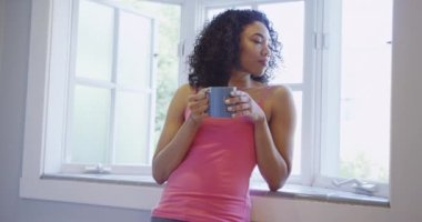 Pencere kenarında kahve içen çekici siyah kadın.