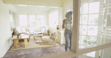 Afrikalı kadın eve dönüyor ve koltukta telefon kullanıyor.