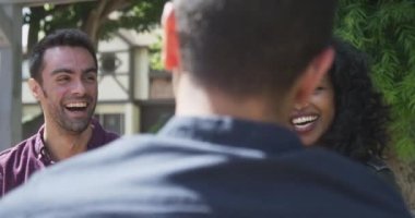 Hipster arkadaşlar açık kafede konuşuyor ve gülüyorlar.