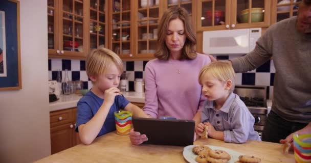 两个可爱的高加索父母和孩子们一起吃饼干和看平板电脑 — 图库视频影像