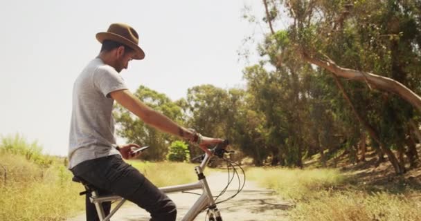 Bisiklet Üzerinde Oturan Smartphone Kullanarak Seksi Genç Adam — Stok video