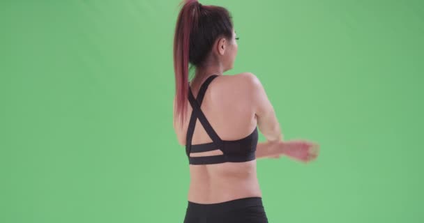 一个年轻的亚洲女人伸展在绿色的屏幕上 在绿色屏幕上键入或合成 — 图库视频影像