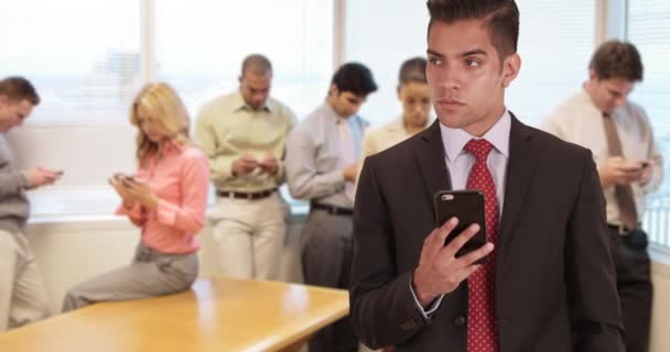 Milenium Biznesmen Smsy Biurze Otoczony Przez Współpracowników Pomocą Własnych Smartfonów — Wideo stockowe