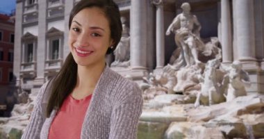 Mutlu çekici Latin kadın Trevi çeşmesinin yanındaki kameraya gülümsüyor. Roma 'da güzel bir günde gülümseyen ve gülen İspanyol turistin sıradan portresi. 4k