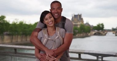 Mutlu genç Afro-Amerikalı çift, Paris 'te Seine Nehri' nin yanında birlikte poz veriyorlar. Sevgili sevgili sevgili bir köprüde birbirlerine yakın durup kameraya bakıyorlar. 4k