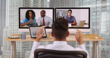 Hispanik iş adamı yüksek katlı şirkette çeşitli iş arkadaşlarıyla internet görüntülü görüşme yapıyor. İş adamı ve uluslararası meslektaşlar VoIP üzerinden iletişim kuruyor