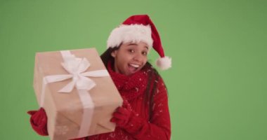 Noel kıyafetli mutlu İspanyol kız yeşil ekranda hediyesini tutuyor. Anahtar ya da birleşik olmak üzere yeşil ekranda.