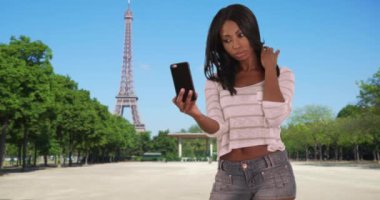 Paris 'te yalnız yaşayan genç bir etnik kadın arkadaşına selfie gönderiyor. Fransa 'da Eyfel Kulesi yakınlarındaki siyahi kadın turist arkadaşlarına mesajla kendi fotoğrafını gönderiyor. 4k