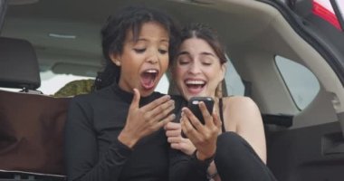 Kız arkadaşlar akıllı telefon kullanarak gülüyorlar.