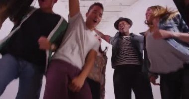 Beyaz stüdyoda dans eden eğlenceli ve genç arkadaşlardan oluşan karışık ırk grubunun düşük açılı görüntüsü.