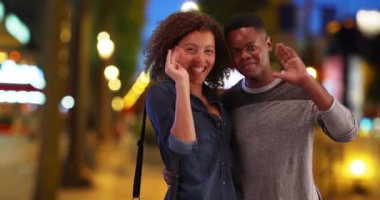 Afrika kökenli Amerikalı çift gece Şanzelize 'de portre için poz veriyor. Siyah adam ve kadın, akşam Paris caddesinde gülümseyip el sallıyorlar. 4k