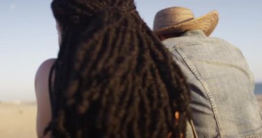 İki siyah kadın arkadaş uzun saçlı sahilde dikiz aynasından bakıyorlar.