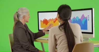 İki ofis çalışanı şirketlerinin istatistikleri hakkında yeşil ekranda konuşuyor. Anahtar ya da birleşik olmak üzere yeşil ekranda.