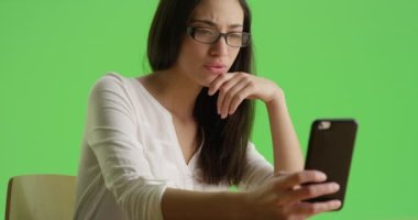 İspanyol bir kadın akıllı telefonunu yeşil ekranda kullanıyor. Anahtar ya da birleşik olmak üzere yeşil ekranda.