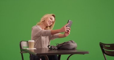 Yeşil ekranda selfie çeken hoş bir kadın. Anahtar ya da birleşik olmak üzere yeşil ekranda.