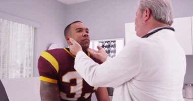 Yakışıklı Afro-Amerikan futbol atleti doktordan spor sakatlığını incelemesini istiyor.