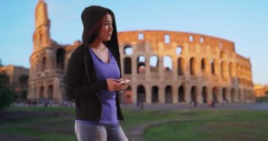 Siyah kapüşonlu Japon kadın Coliseum yakınlarında cep telefonuyla mesajlaşıyor. Roma 'da ciddi bir Asyalı kadın mesajlaşması. 4k