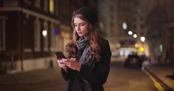 千年白人黑发女人独自站在街上用她的智能手机发短信 年轻的女士在找她的朋友试图用她的手机联系他 — 图库视频影像