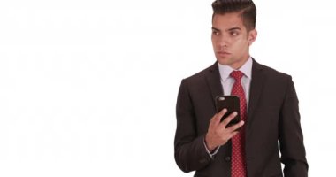 İş adamı beyaz arka planda sosyal medyada mesajlaşıyor ya da kullanıyor. İspanyol milenyum adamı takım elbiseli ve arka planda fotokopi alanı ve akıllı telefonla sıkı bir kravat takıyor. 4k