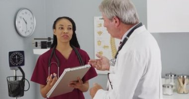 Tecrübeli kıdemli doktor genç hemşireyle konuşuyor.