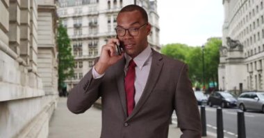Londra 'daki genç, Afro-Amerikalı iş adamı dışarıda bir müşteriyle telefonda sohbet ediyor. Şehir ortamında akıllı telefonunu kullanan siyahi bir profesyonel. 4k