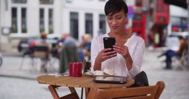 Güzel bir kadın Bruges 'de bir kafede oturuyor, Belçika' da bir arkadaşıyla akıllı telefonunda video sohbetleri yapıyor. Bruges 'de bir restoranda oturan genç siyahi kadın telefonunu kullanıyor. 4k
