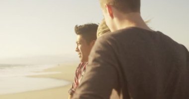 Arkadaşlar kumun üzerinde durup okyanusa bakıyorlar.