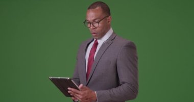 Siyahi bir yönetici yeşil ekranda tableti üzerinde çalışıyor. Anahtar ya da birleşik olmak üzere yeşil ekranda.