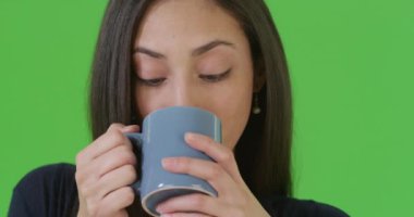 Yeşil ekranda kahve içen İspanyol bir kadının yakın plan portresi. Anahtar ya da birleşik olmak üzere yeşil ekranda.