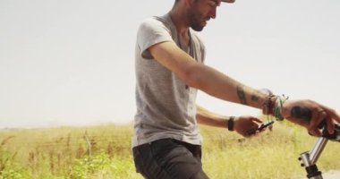 Bisiklet üzerinde oturan ve smartphone kullanarak seksi İspanyol erkek