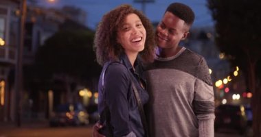 Milenyum Afrikalı Amerikalı çift San Francisco 'da gece bir portre için poz veriyor. Genç siyahi bir adam ve bir kadın gece şehrin dışında dikiliyorlar. 4k.