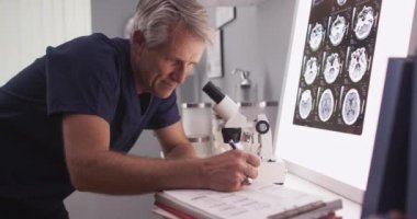 Olgun beyaz nörolog erkek röntgene bakıyor.