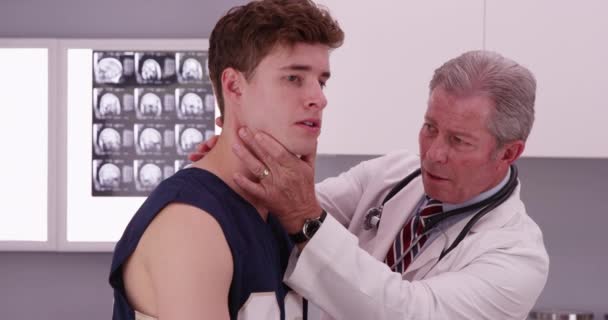 中間老化させた医者の肖像画はスポーツ選手の首の負傷をチェックします — ストック動画