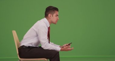 Genç İspanyol iş adamı ofis koltuğunda oturmuş yeşil ekranda iş arkadaşıyla konuşuyor. Anahtar ya da birleşik olmak üzere yeşil ekranda.