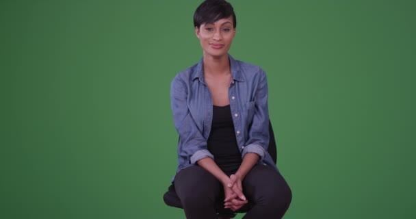 緑の画面にデニムシャツを着た若いアフリカ系アメリカ人女性がオフィスの椅子でカメラを笑っている姿が描かれている 緑の画面でキーまたは構成されます — ストック動画