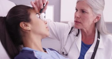 Kıdemli tıp doktoru futbolcunun gözlerini fenerle kontrol ediyor.