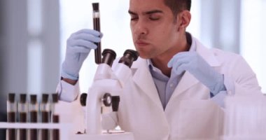 Ofisteki yakışıklı İspanyol bilim adamı deney tüpüne bakıyor. Milenyum tıp araştırmacısı laboratuarda mikroskoptan bakıyor. 4k