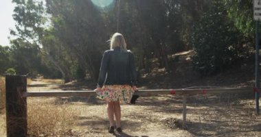 Genç ve çekici beyaz kız toprak yolda oturuyor.