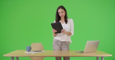 Latin bir iş kadını yeşil ekranda tabletini kullanıyor. Anahtar ya da birleşik olmak üzere yeşil ekranda.