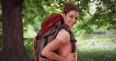 Aktif bir beyaz kadın, yemyeşil bir doğa ortamında yürüyüşe çıkmış. Huzurlu bir ormanda yürüyüş yaparken büyük bir sırt çantası takan genç beyaz bir kadın. 4k