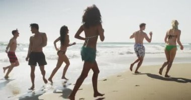 Çok etnik arkadaş atlama plaj sahil çalışan sağlıklı grubu