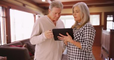 Tablet bilgisayara bakan olgun bir çift. Akıllı bir tablet kullanırken mutlu karı-koca konuşuyor..