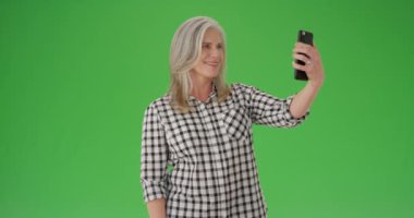Güzel beyaz kadın cep telefonuyla selfie çekiyor.