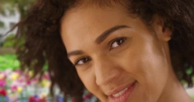 Kameraya gülümseyen ve gülen neşeli siyahi bir kadının yakın çekimi. Lale bahçesinde gülümseyen genç bir kadının yavaş çekim çekimi. 4k