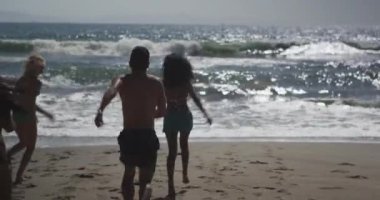 Sahilde oynayan genç bir arkadaş grubunun izini sürüyorum.